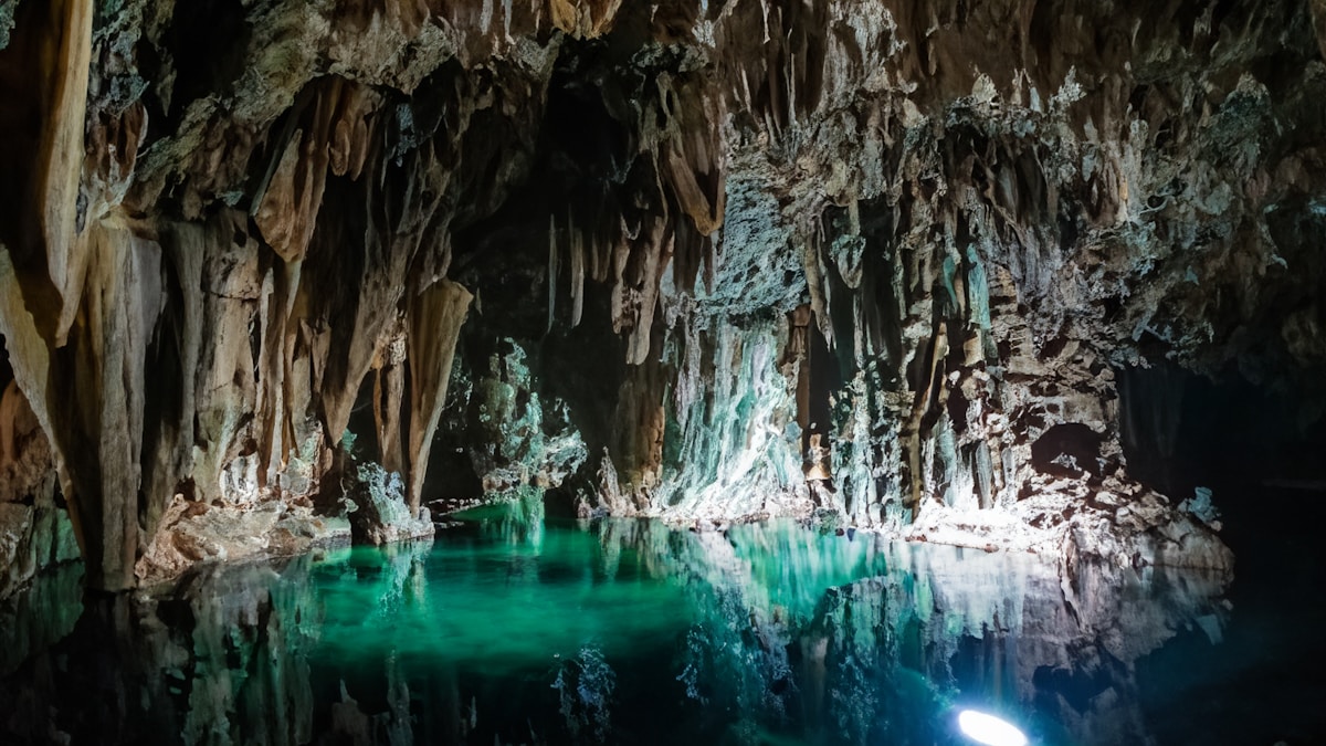 Caverna sotterranea con acqua verde luminosa — ambientazione Core Keeper